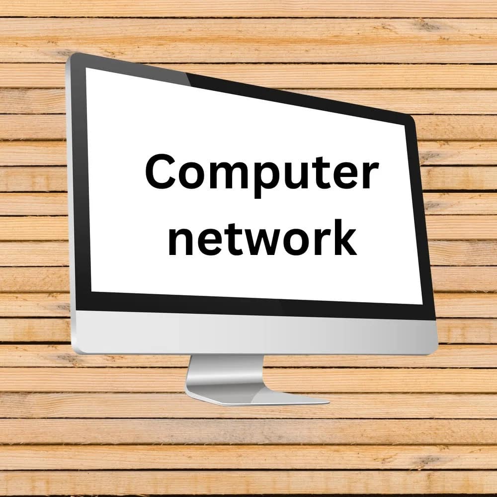 A computer monitor displaying the words Computer network and types of computer network on a white screen, set against a wooden plank background.